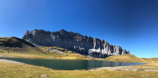 Scenic view of lake and mountains against clear blue sky