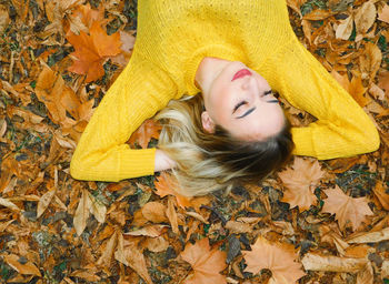 High angle view of woman lying on yellow leaves