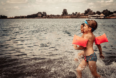 Cheerful kids running through water and having fun in summer day at the beach.