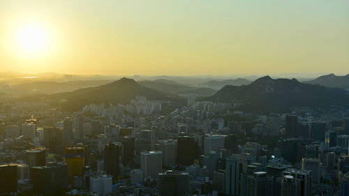 Aerial view of buildings in city against sky during sunset