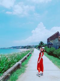 Side view of woman standing on shore against sky