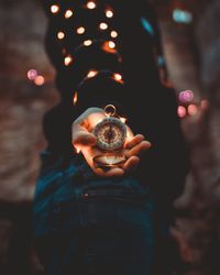 Close-up of hand holding navigational compass at night