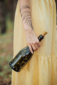 Enchantment, magic, midsummer ritual. woman with fern tattoo holding bottle with lights inside.