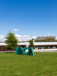 View of house and plants on field against blue sky