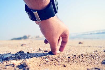 Low section of man on beach against clear sky