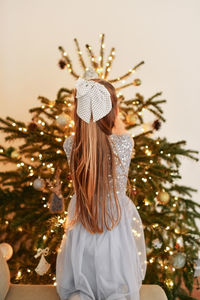 A small girl decorates a christmas tree