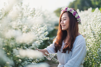 Smiling woman standing by flowering plants