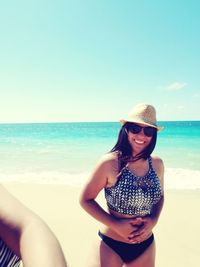 Portrait of young woman wearing sunglasses standing at beach