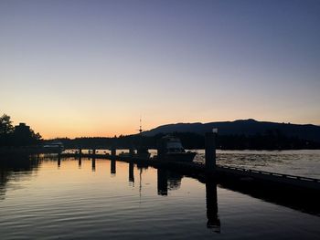 Boats on lake against clear sky during sunset