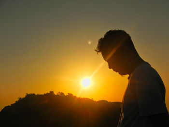 Side view of silhouette man standing against sky during sunset