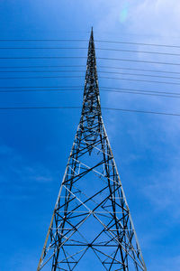 Low angle view of electricity pylon against blue sky