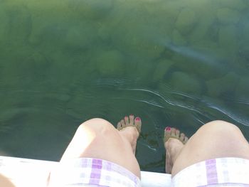 Low section of woman sitting by lake