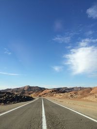 Road passing through landscape against blue sky