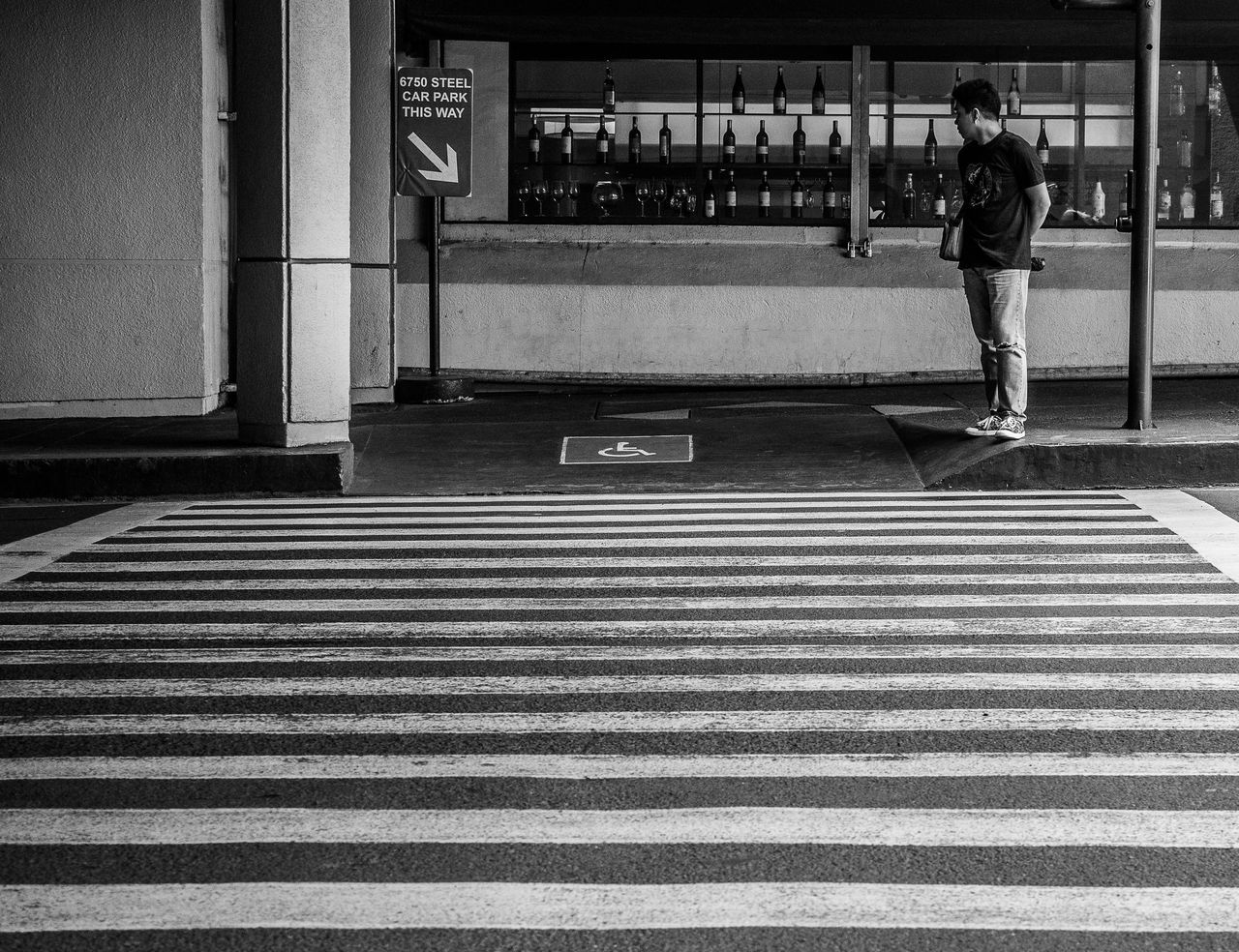 REAR VIEW OF MAN CROSSING ROAD AT CITY