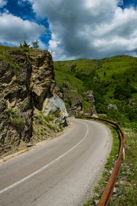 Road amidst green landscape against sky