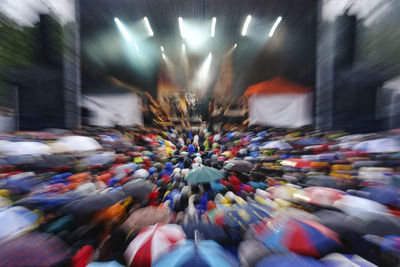 Crowded music festival with fans carrying umbrellas