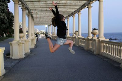 Girl jumping in colonnade by the sea