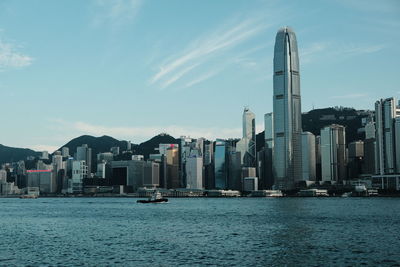 Sea by modern buildings against sky in city