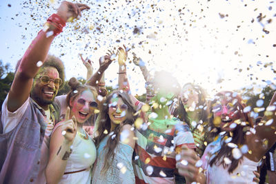 Confetti over happy friends dancing at carnival