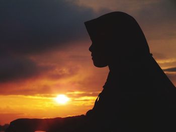 Close-up silhouette of teenage girl against sky during sunset