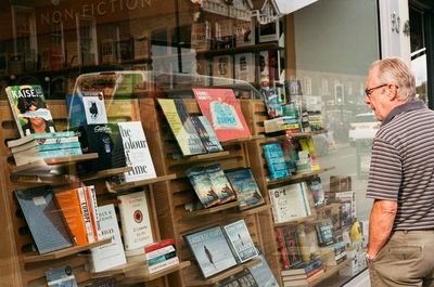 Midsection of man reading book at store