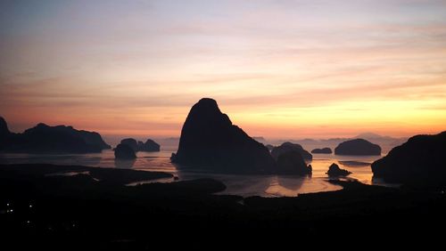 Rocks in sea against sky during sunset