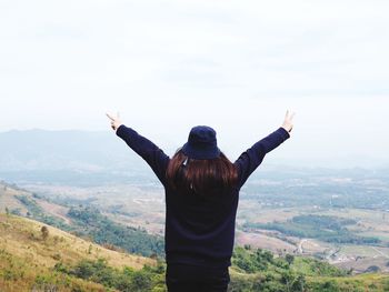 Rear view of man with arms outstretched standing on landscape