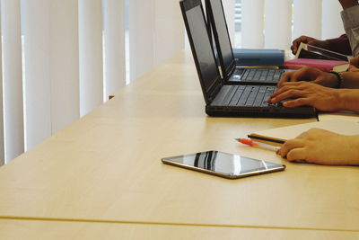 Cropped hands of student using laptop in classroom