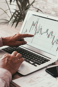 Cropped hands of businessman using laptop on table