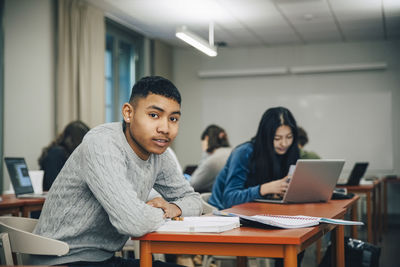 Portrait teenage boy sitting at desk in classroom