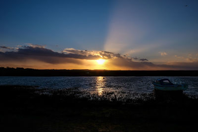 Silhouette boats moored in lake against sky during sunset