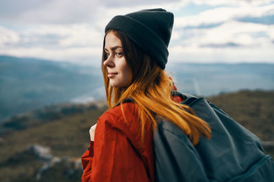 Beautiful young woman looking at mountains against sky