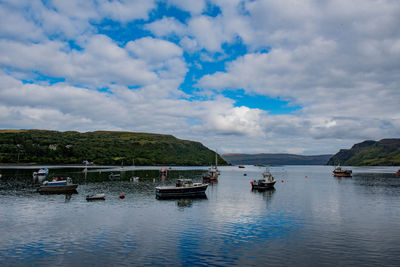 Sailboats moored in sea against sky