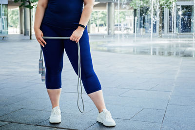 Faceless plus size curvy happy young woman with skipping rope outdoors. curvy woman with skipping