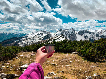 Midsection of person holding snowcapped mountain against sky