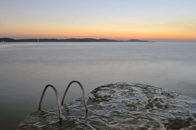 Jetty against sea at sunset