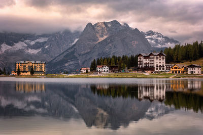 Buildings by lake against sky