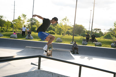 Rear view of people jumping against sky