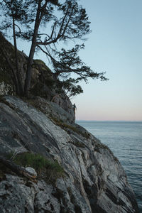 Rock formation by sea against clear sky