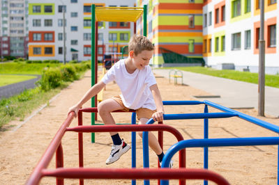 The boy does sports on horizontal bars of different colors