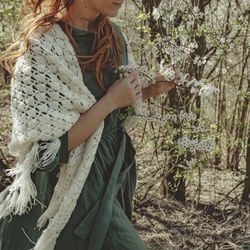 Midsection of woman standing by flowering tree