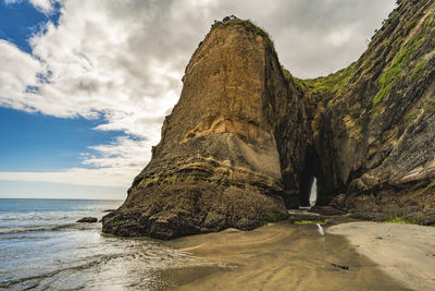 Rock formation on beach against sky