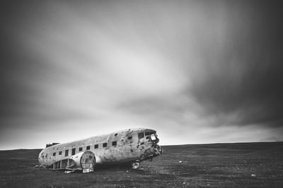 Abandoned airplane on beach against sky