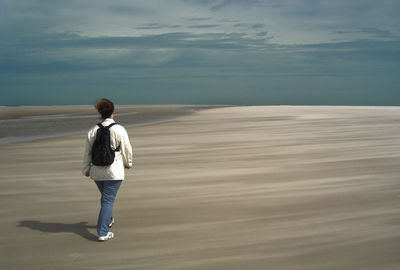 Rear view of woman walking at beach