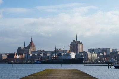 View of buildings by river against sky in rostock 