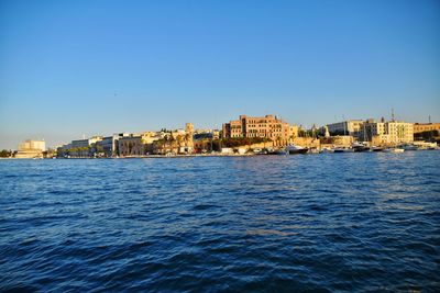 Sea by buildings against clear blue sky