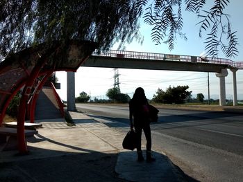 Rear view of woman walking on road against sky