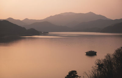 Scenic view of lake and mountains against sky during sunset