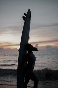 Low angle view of silhouette person on beach against sky during sunset