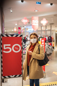 Full length portrait of smiling woman standing in store